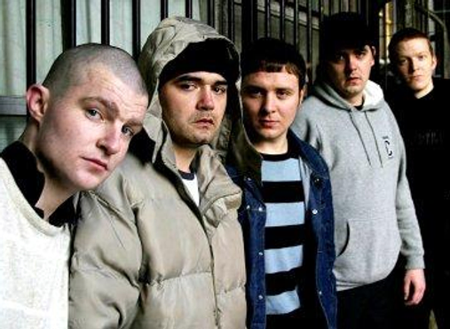 Photo of threatening-looking youths lined up against a wall, on of them in hooded jacket, another with shaven head