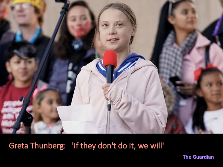 Photo of a young Greta Thunburg at podium holding mic, making a speech. In the backtround are other children, out of focus