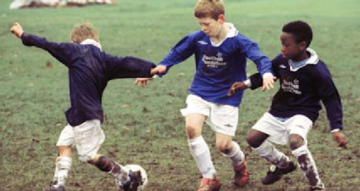 Photo of boys playing football in a muddy field